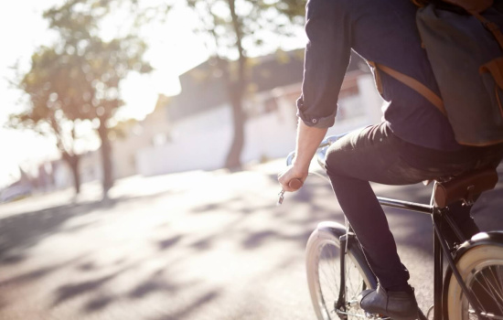 man som cyklar på gata i solljus med träd